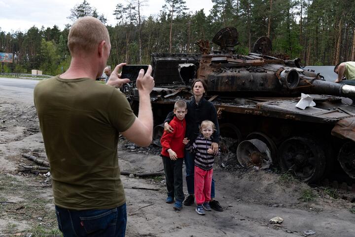 Семья фотографируется на фоне уничтоженного российского танка в окрестностях Киева. Фото: Reuters